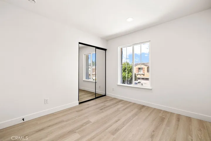 Secondary bedroom with mirrored closet doors and abundant natural light.