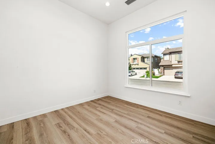 Bright secondary bedroom with large window and neighborhood views.