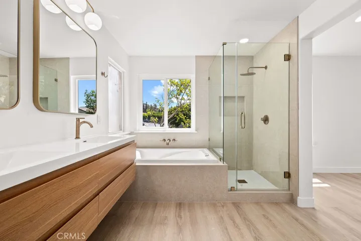 Spacious primary bathroom featuring dual vanities, soaking tub, and separate glass-enclosed shower.