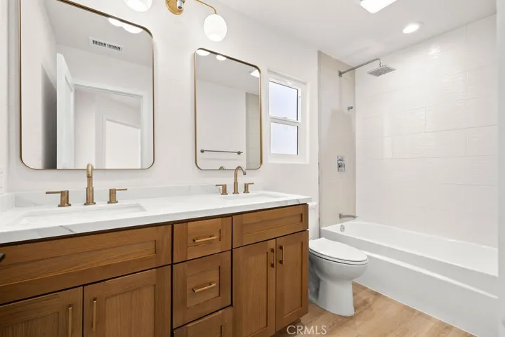 Secondary full bathroom with dual sinks, updated vanity, and tub/shower combination.
