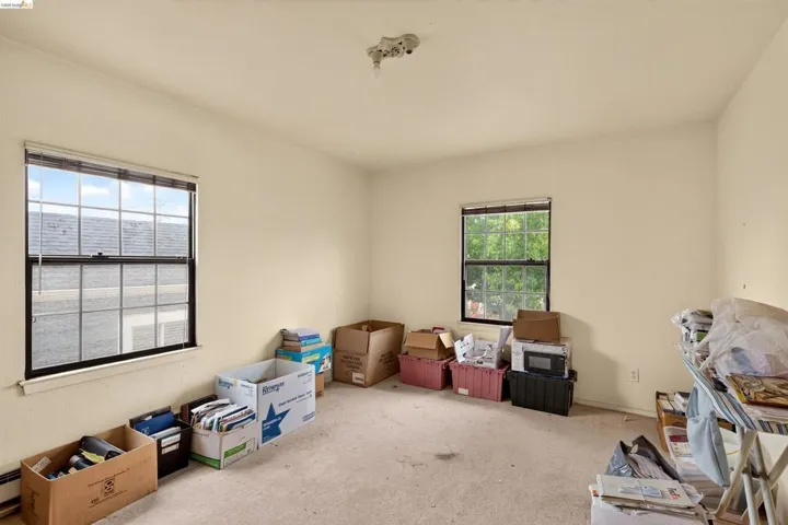 Neutral wall paint, two windows with black frames, and beige carpet flooring