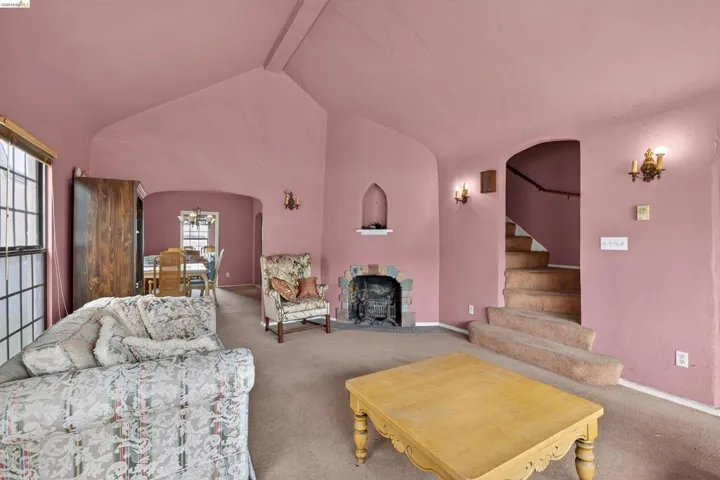 Living area featuring vaulted ceilings, a fireplace with a stone surround, and an arched entryway