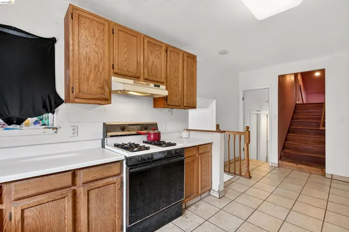 Kitchen space featuring wood-finish cabinetry, white countertops, and a built-in range with an overhead exhaust hood