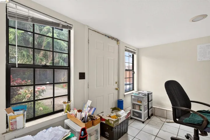 Light-filled interior space featuring grid-pattern windows, a standard entry door, neutral wall paint, recessed ceiling lighting, and white tile flooring