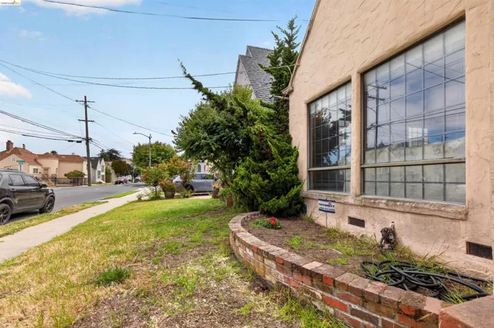 Stucco exterior featuring large multi-pane windows and a brick planter bed