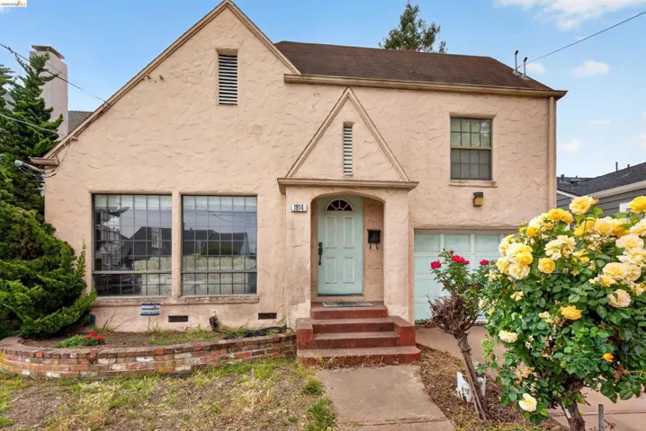 Stucco exterior featuring a prominent gabled roofline and an arched entry with a light blue door