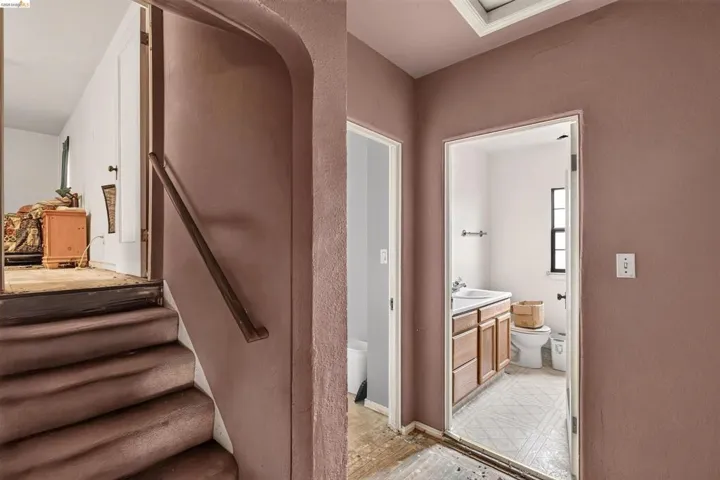 Carpeted staircase with wooden handrail leading to a landing with a visible doorway