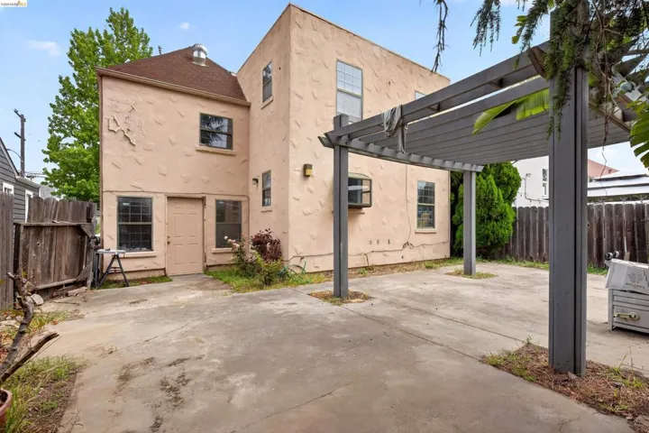 Rear exterior with a concrete driveway and an attached pergola