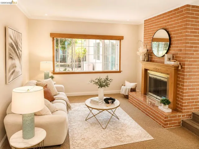 Living area featuring a brick fireplace with a wood mantle, a large window with grid panes, and neutral tone walls