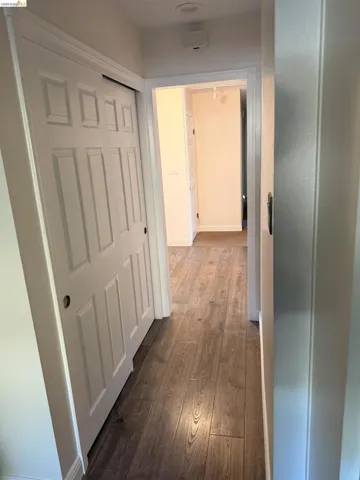 Hallway featuring wood-finish flooring, white paneled doors, and recessed lighting