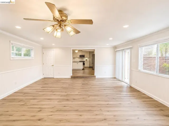 Spacious room featuring wood-finish flooring, white wainscoting, and recessed lighting