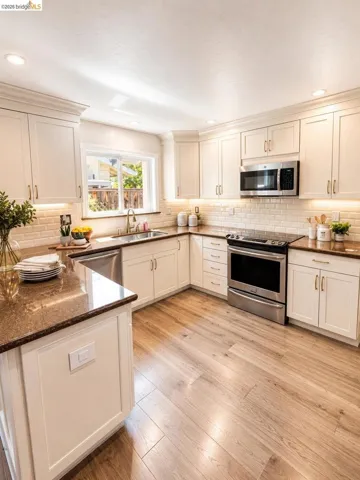 Contemporary kitchen featuring white cabinetry, wood-finish flooring, and dark speckled countertops