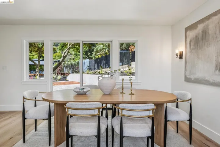 Dining area featuring wide plank wood-finish flooring, white baseboards, and a wall-mounted sconce