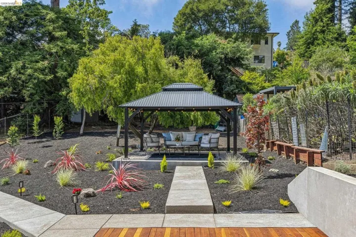 Outdoor gazebo with a metal roof and string lighting, set on a concrete pad with seating