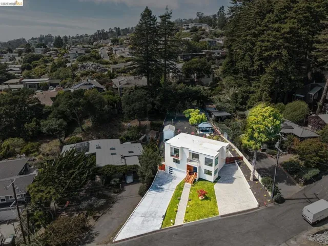 Contemporary architectural home featuring a white exterior, a red front door, a driveway, a garage, and a manicured lawn area