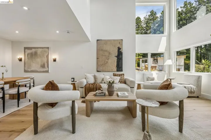 Bright living space featuring expansive windows, high ceilings, wood-finish flooring, and recessed lighting
