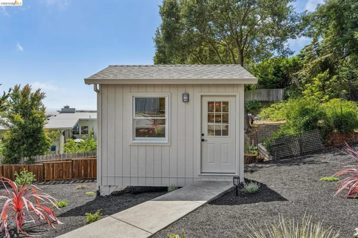 Detached structure featuring vertical siding and a shingled roof