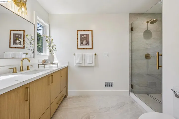 Contemporary bathroom with a floating wood-finish vanity, integrated sink, and gold-tone hardware