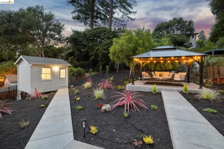 Landscaped yard featuring a freestanding storage shed and a covered gazebo on a concrete pad