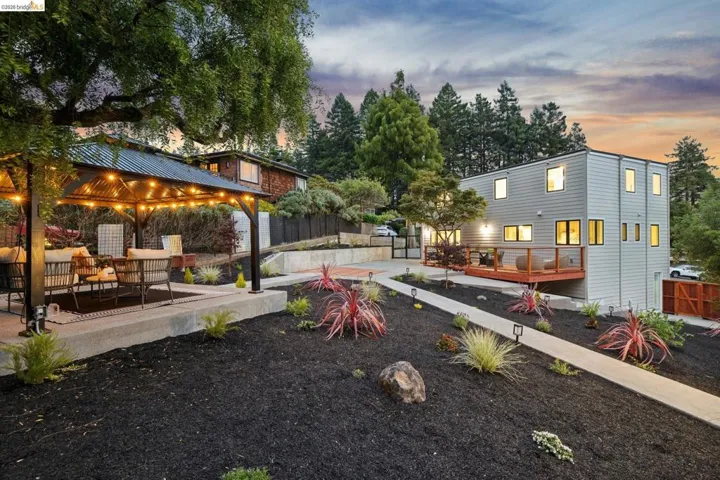 Multi-level exterior featuring a contemporary house with light grey siding and a ground-level deck