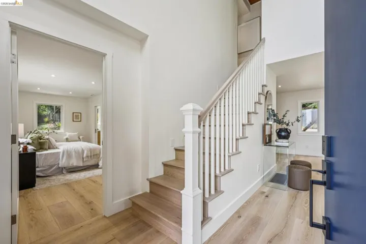 Foyer featuring wood-finish flooring, a white staircase with wood treads, and a blue entry door with black hardware
