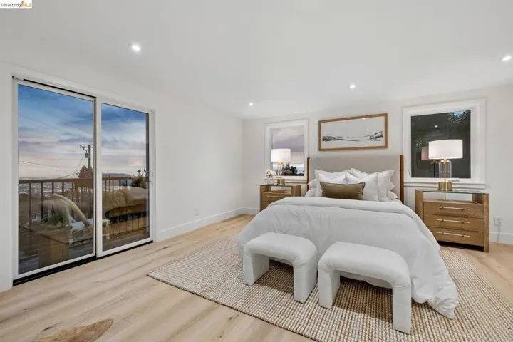 Recessed lighting illuminates a spacious room featuring wide plank wood-finish flooring and a large sliding glass door with balcony access