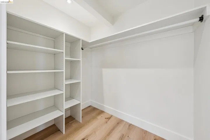 Custom closet system featuring multiple adjustable shelves, a long hanging rod, and wood-finish flooring