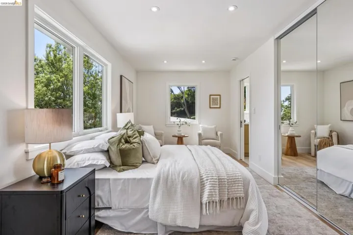 Spacious bedroom featuring multiple windows, recessed lighting, mirrored closet doors, and carpet flooring