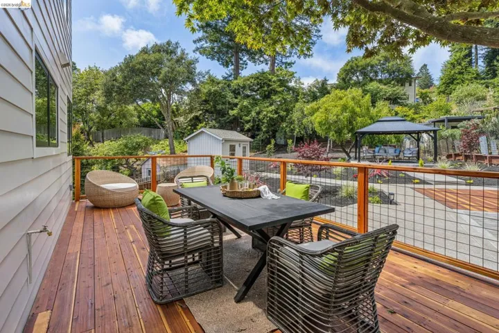 Expansive wood deck with horizontal siding, a wire mesh railing, and a detached shed