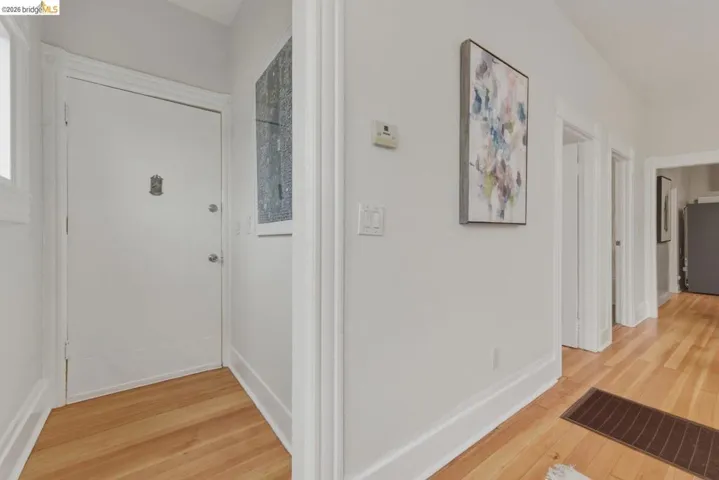 Hardwood flooring throughout the entry area, featuring white trim and baseboards