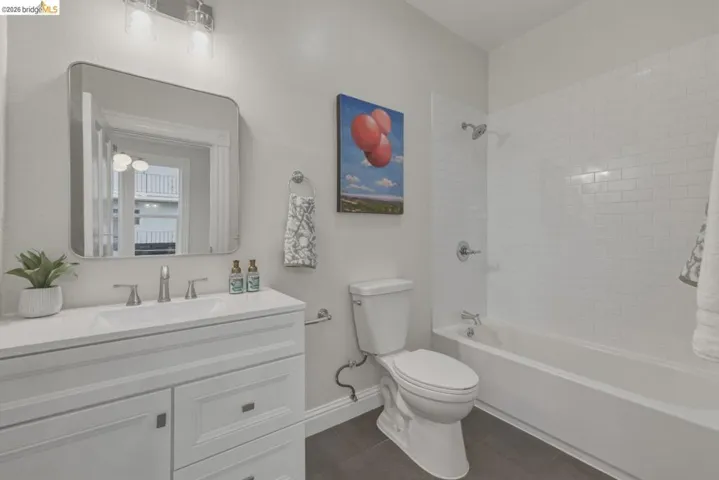 Bathroom featuring a white vanity with integrated sink, chrome fixtures, and a rounded rectangular mirror