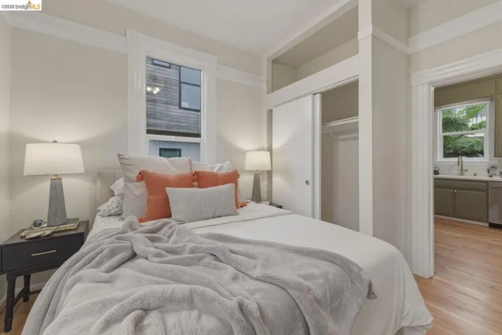 Bedroom featuring hardwood flooring, a built-in closet with sliding doors, crown molding, and a window with white trim