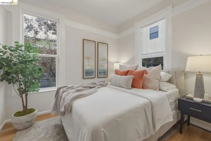 Naturally lit room featuring dual windows with white trim, crown molding, light wood-finish flooring, and light-toned walls