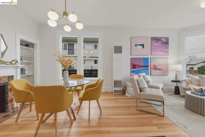 Open concept living area featuring wood-finish flooring, a decorative fireplace with tile surround, built-in shelving, and a modern chandelier