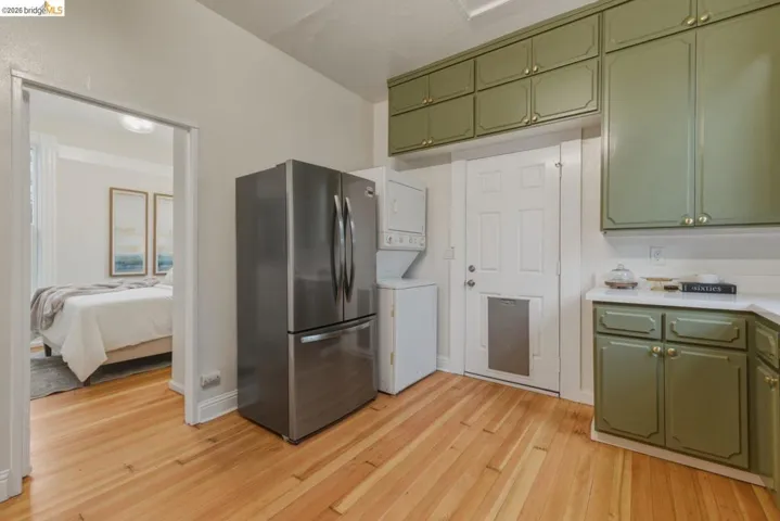 Kitchen featuring ample green cabinetry, white countertops, stainless steel refrigerator, and wood-finish flooring