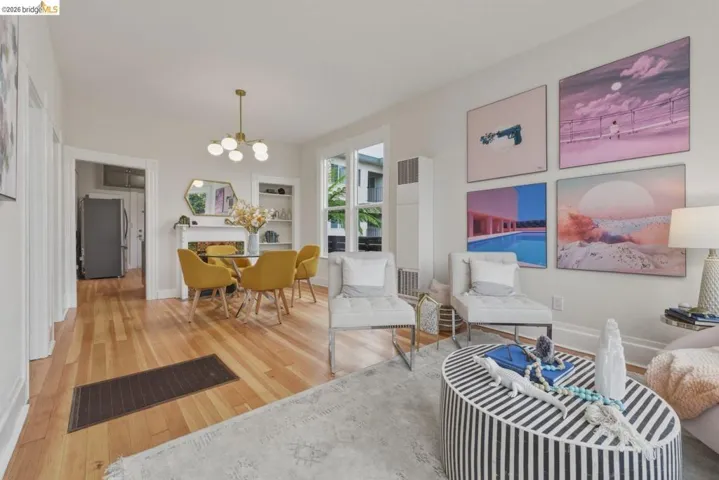 Spacious living area featuring polished wood-finish flooring, a contemporary ceiling light fixture, and large windows providing natural light