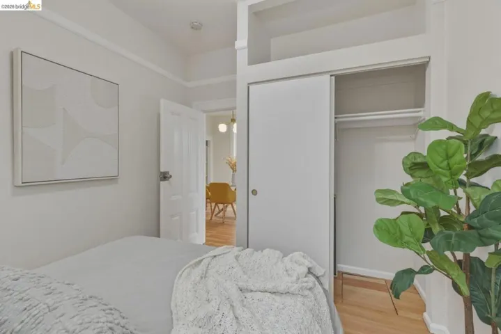 Bedroom featuring light-toned walls, crown molding, and wood-finish flooring