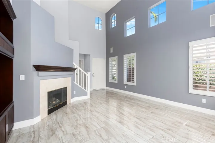 Living Room with Tile Flooring, Fireplace, High Ceilings and Plantation Shutters.