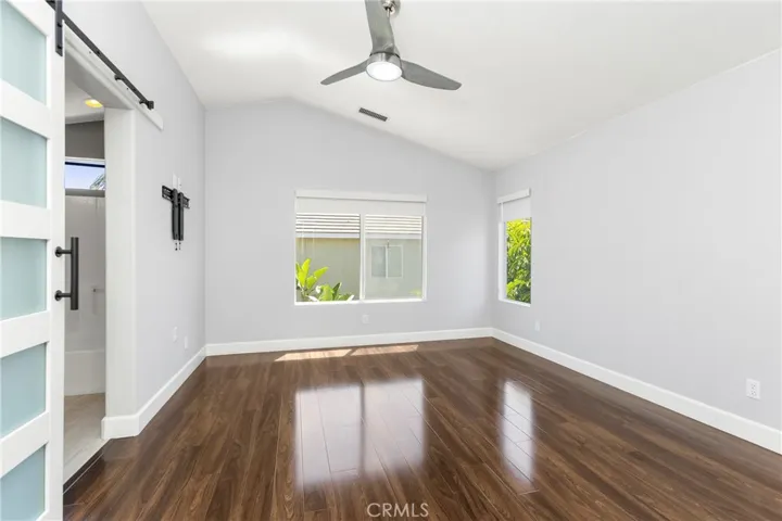 Primary Bedroom with Engineered wood flooring, ceiling fan and Barn door to the bathroom
