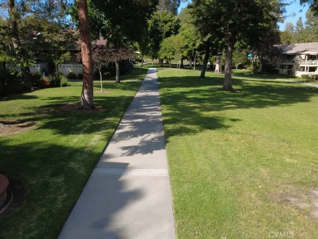 A charming sidewalk leads through expansive greenbelts, reflecting the serene, park-like atmosphere just outside the home's front door.