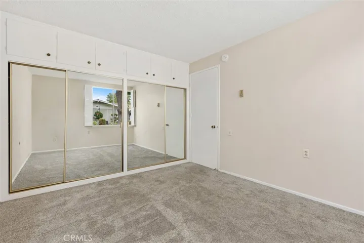 Another view of the secondary bedroom showcases mirrored closet doors and a spacious layout filled with natural light.