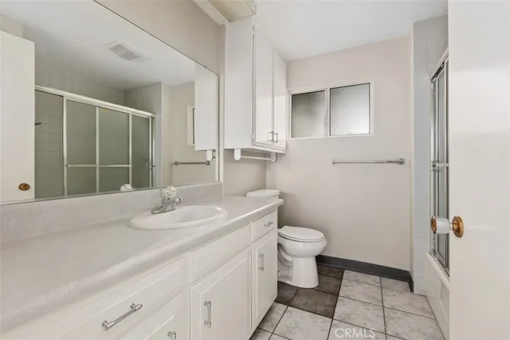 The bathroom features an oversized vanity with abundant storage, a spacious shower/tub combo, and tasteful finishes.