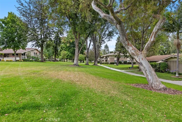 Scenic walking paths wind through beautifully maintained lawns beneath a canopy of mature trees, creating a tranquil neighborhood setting.