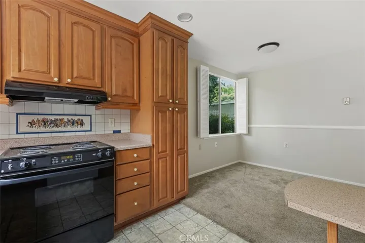 Another view of the remodeled kitchen highlights its generous cabinetry, convenient layout, and adjacent casual dining space.