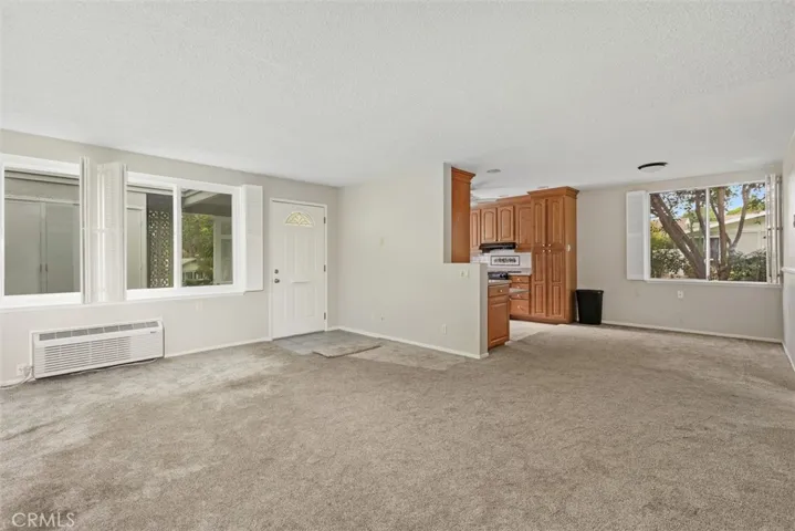 Another view of the spacious living room highlights the open floor plan, abundant natural light, and newly installed luxury carpeting throughout.