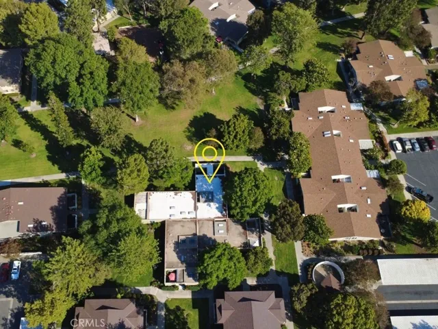 An aerial perspective showcases the home's exceptional location surrounded by mature trees, open greenbelts, and beautifully landscaped common areas.