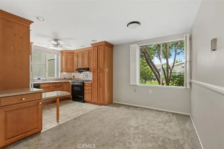 The remodeled kitchen features abundant cabinetry, generous countertop space, and a bright informal dining area overlooking the surrounding greenery.