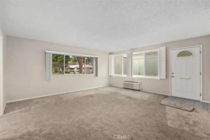 The expansive living area offers flexible furniture arrangements and oversized windows that frame tranquil greenbelt views while filling the space with natural light.