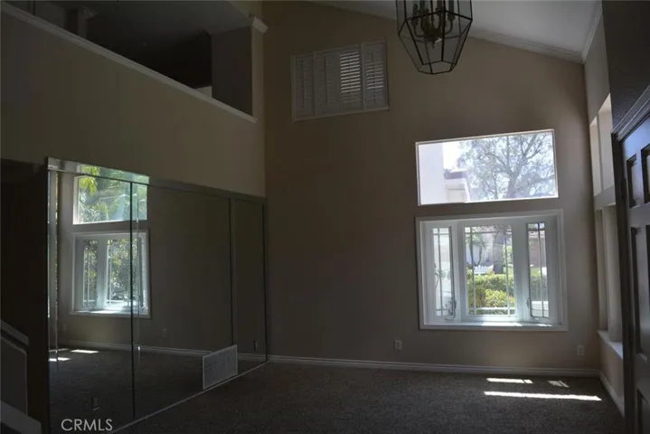 Living room with lots of light and cathedral ceilings just off of double door entry.
