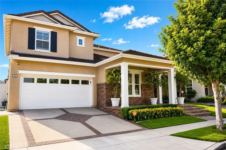 Beautifully maintained exterior featuring a welcoming covered porch, nice landscaping, and an oversized two-car garage.